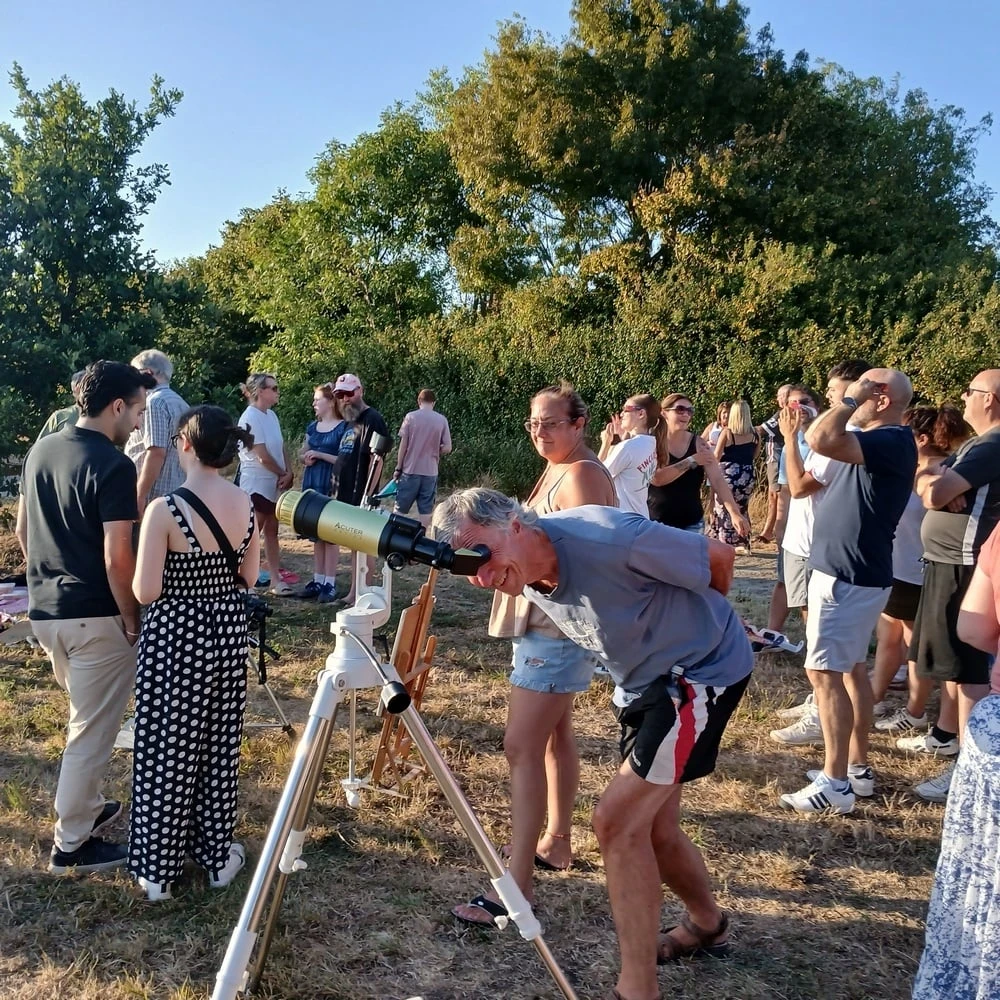 A crowd of villagers queueing to look through a small telescope during the 12 August 2026 solar eclipse