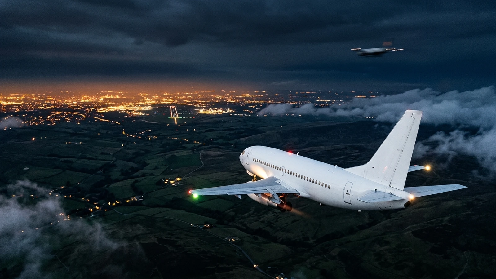 A Boeing 737 airliner descending at night over the Pennines with the lights of Manchester below and a small lit object passing to its right