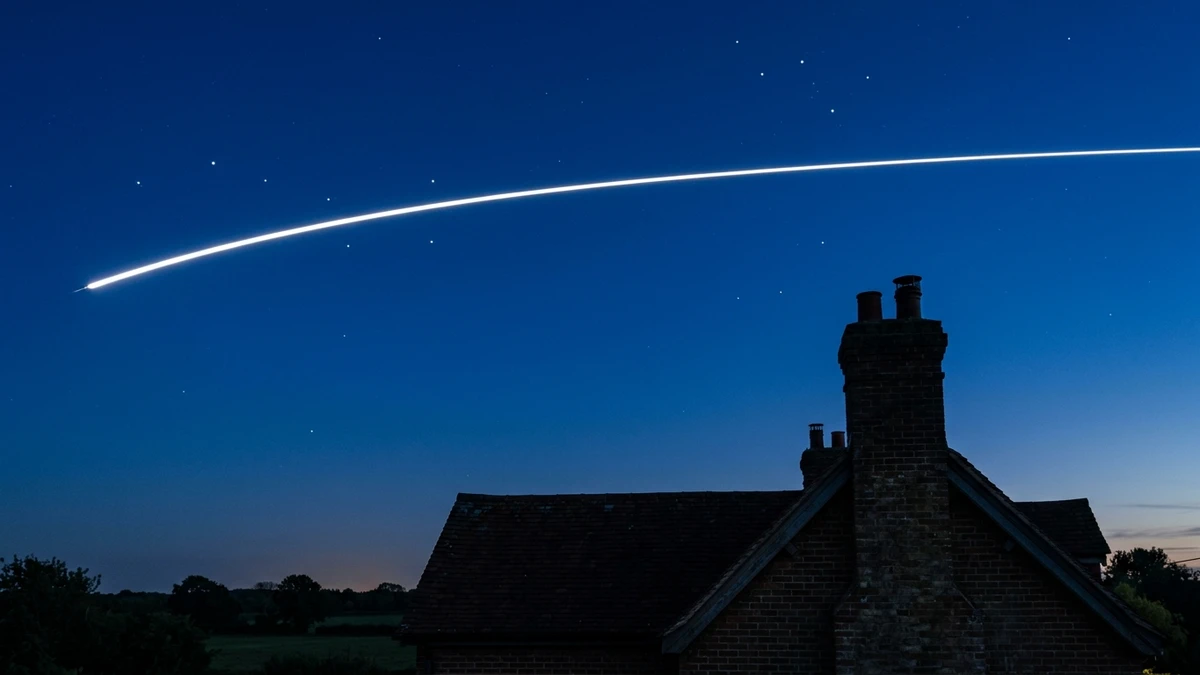 A bright streak of the International Space Station arcing over a UK house rooftop at dusk with a few stars visible