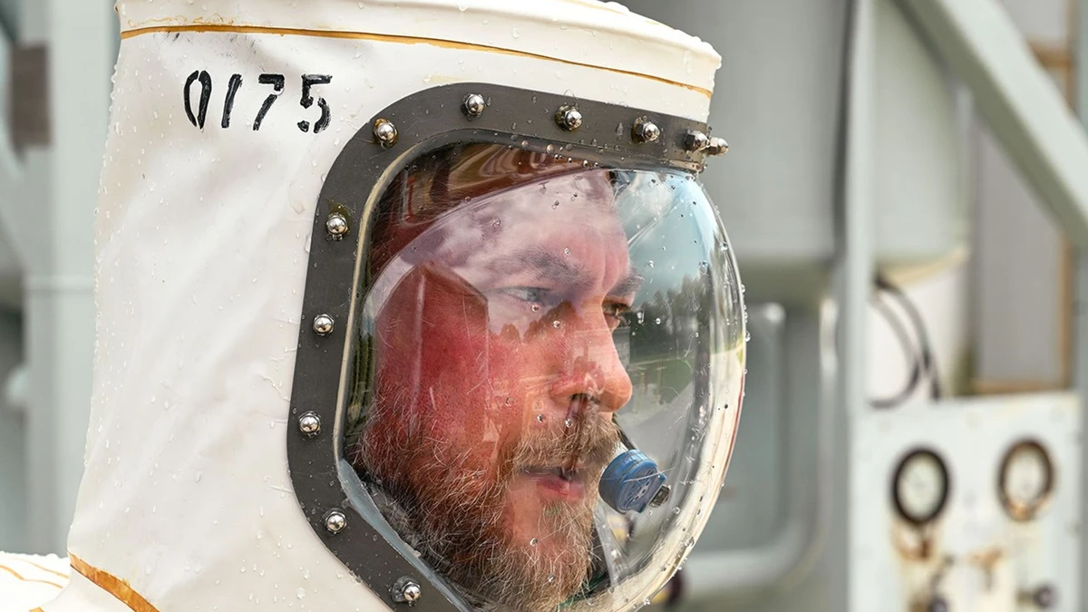 A NASA technician in a white pressurised SCAPE protective suit preparing to load hydrazine propellant into the Roman Space Telescope at Kennedy Space Center