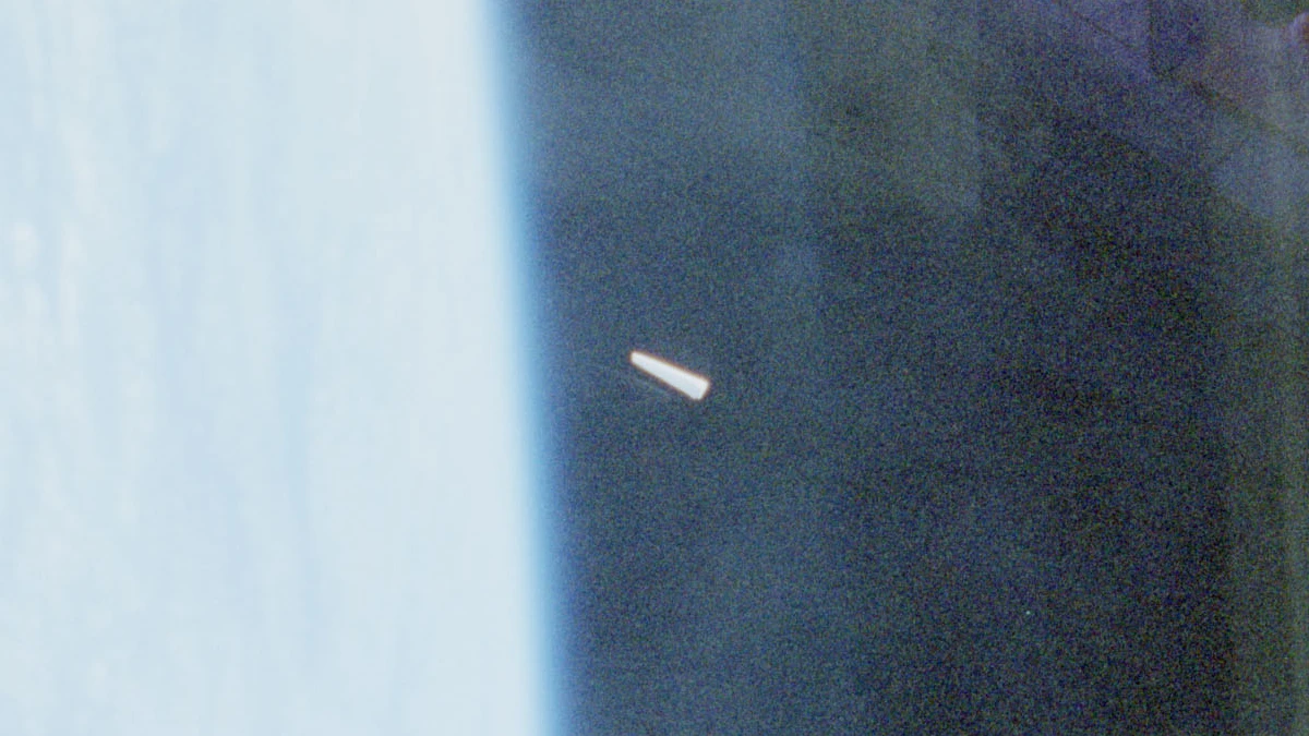 Native-resolution detail crop of the STS-80 unidentified object: a bright white tapered shape against dark sky