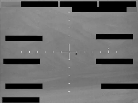 Redacted sensor image with a crosshair targeting an object.