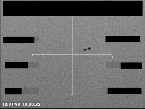 Redacted sensor image with a crosshair targeting a visible object.