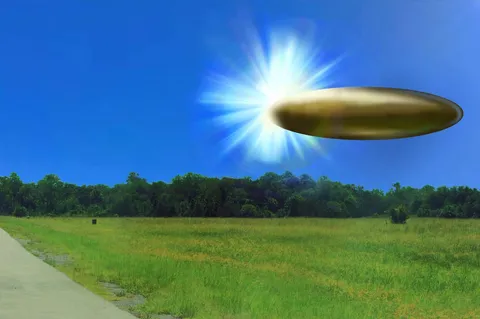 Saucer-shaped object with a bright light hovers over a grassy field.